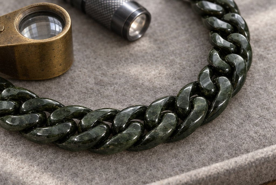 Dark green jade Cuban link bracelet on a jeweller's felt pad with a loupe and a small torch