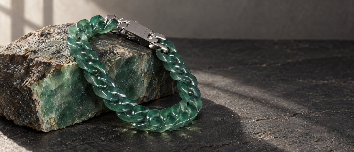 Green jade Cuban link bracelet resting on a raw block of jade