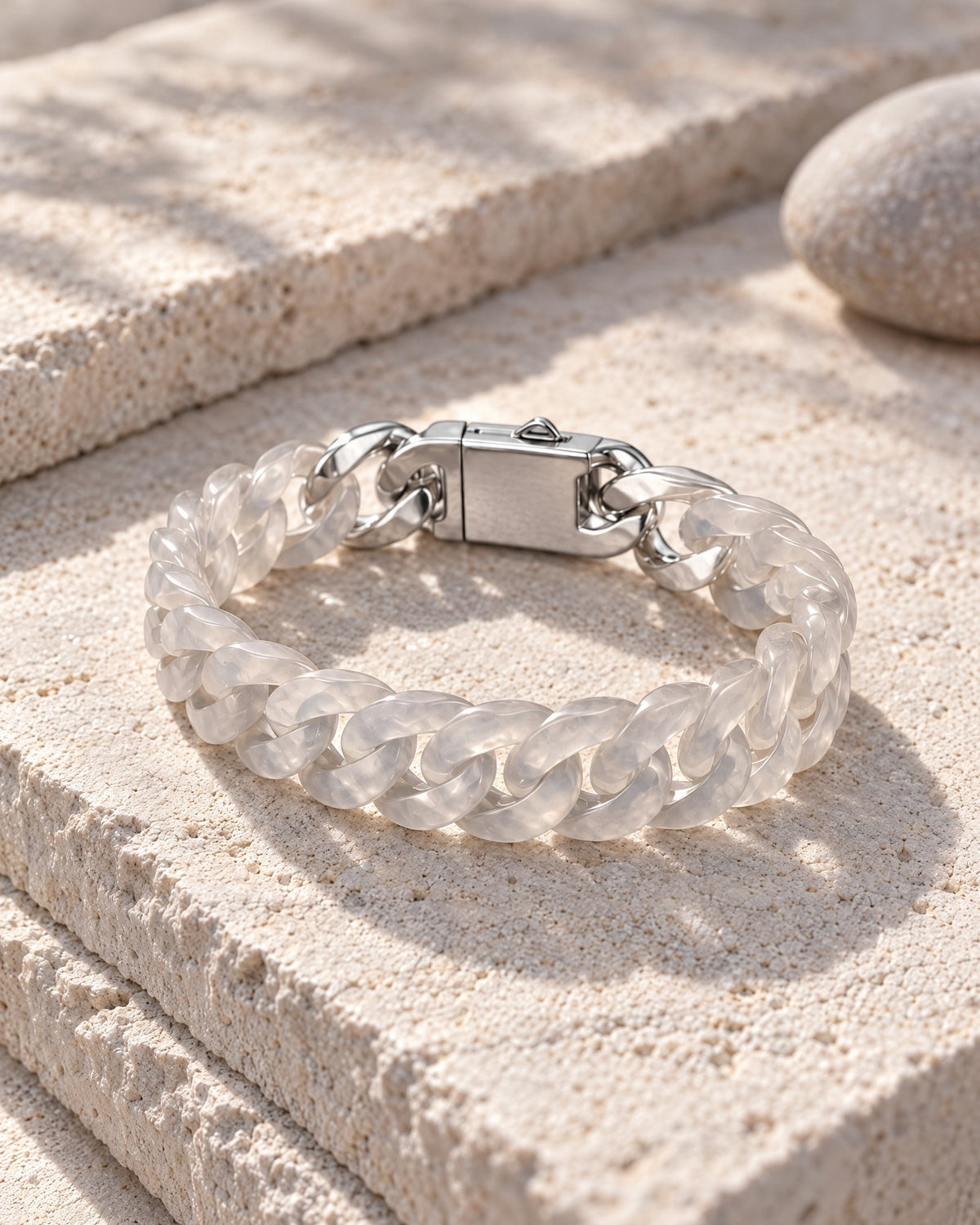 Classic Cuban Link Chain Bracelet In White Agate resting on its side on pale stone in soft daylight