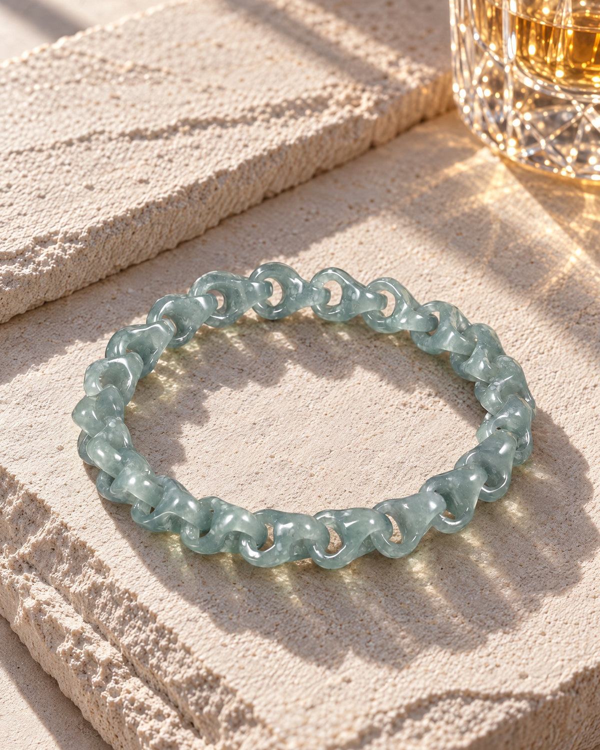Single Piece Carved Dragon Spine Cable Chain Bracelet In Green Jade on pale limestone in warm sunlight