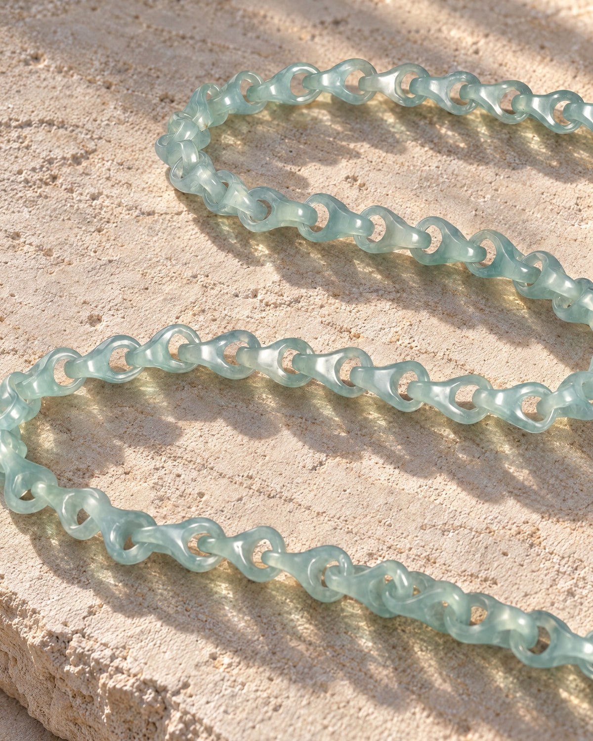 Single-piece carved dragon spine jade necklace on limestone in warm sunlight