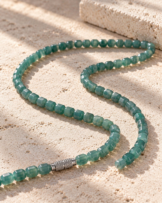 Faceted Barrel Bead Necklace In Guatemalan Jade on white stone: Pale limestone tabletop